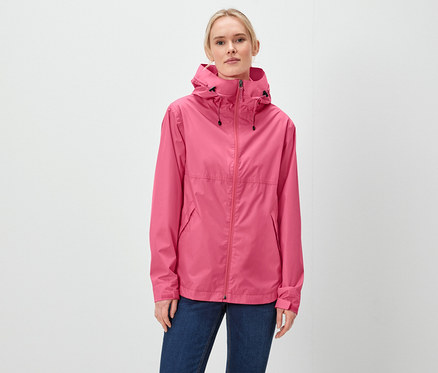 Une femme porte une veste rose à capuche et un jean bleu.