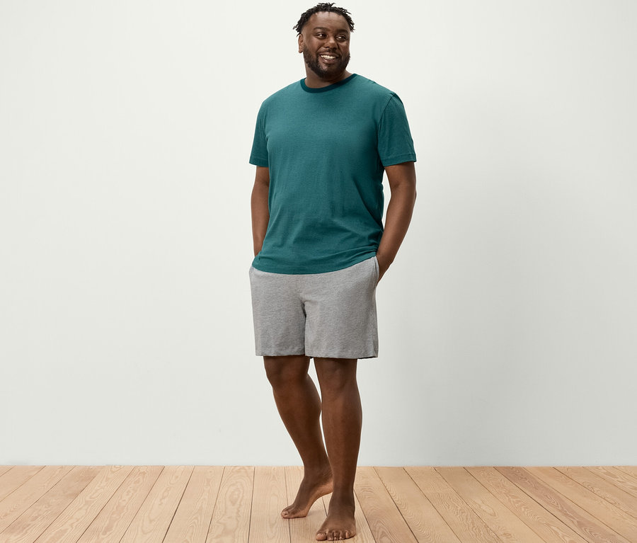 Un homme se tient debout, les mains dans les poches de son ensemble pyjama shorty.