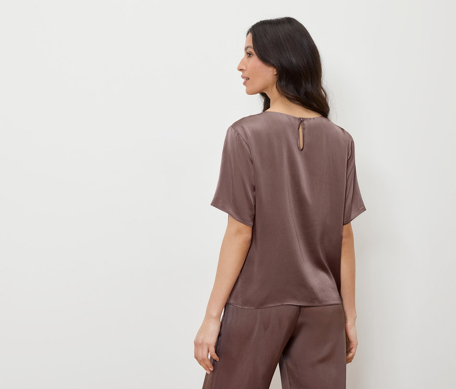 Femme en haut et pantalon de satin marron, regardant vers la gauche.