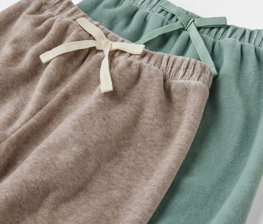 Gros plan sur deux paires de Baby-Pull-on-Pants, une beige, une verte.