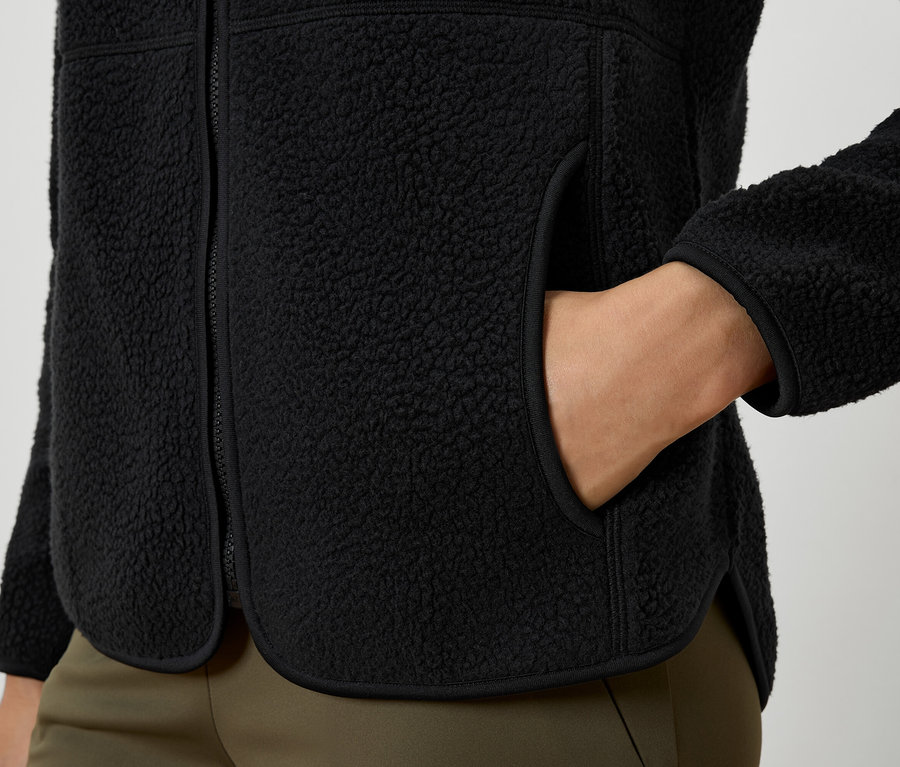 Gros plan d'une veste en polaire noire avec une main dans la poche.
