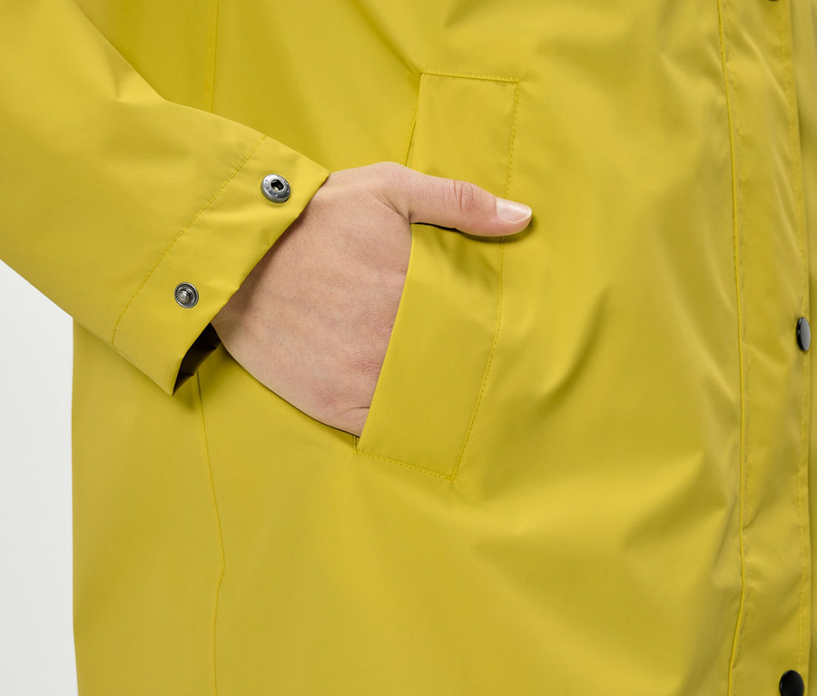 Main dans la poche d'un manteau jaune.