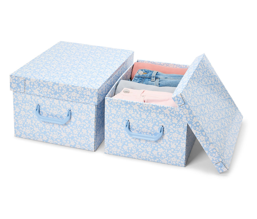 Deux boîtes de rangement avec couvercle à motif floral bleu. Une boîte est fermée et l'autre est ouverte et pleine de vêtements.