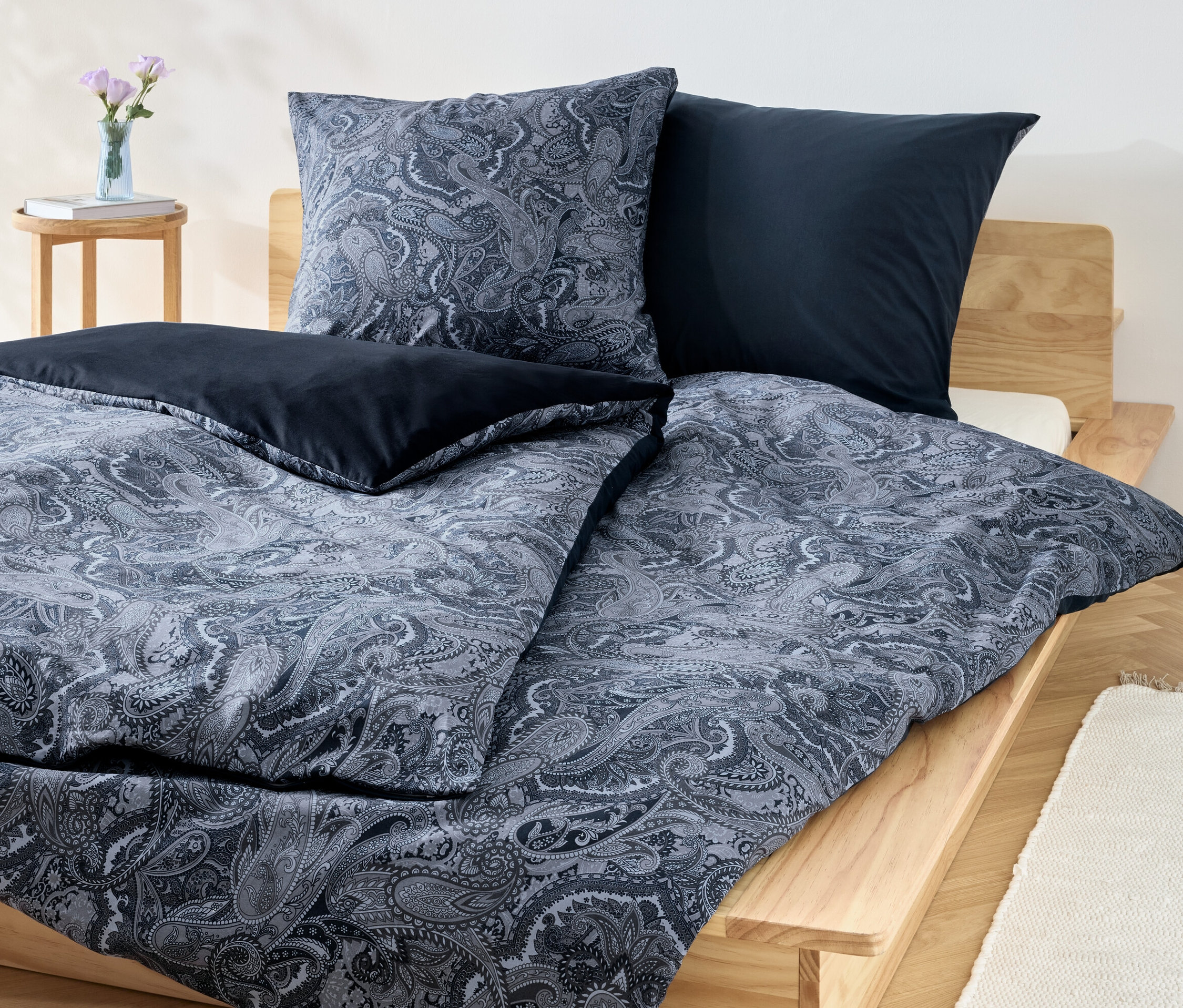 Un ensemble de literie bleu en renforcé avec un motif floral et des oreillers bleus unis sur un lit en bois.