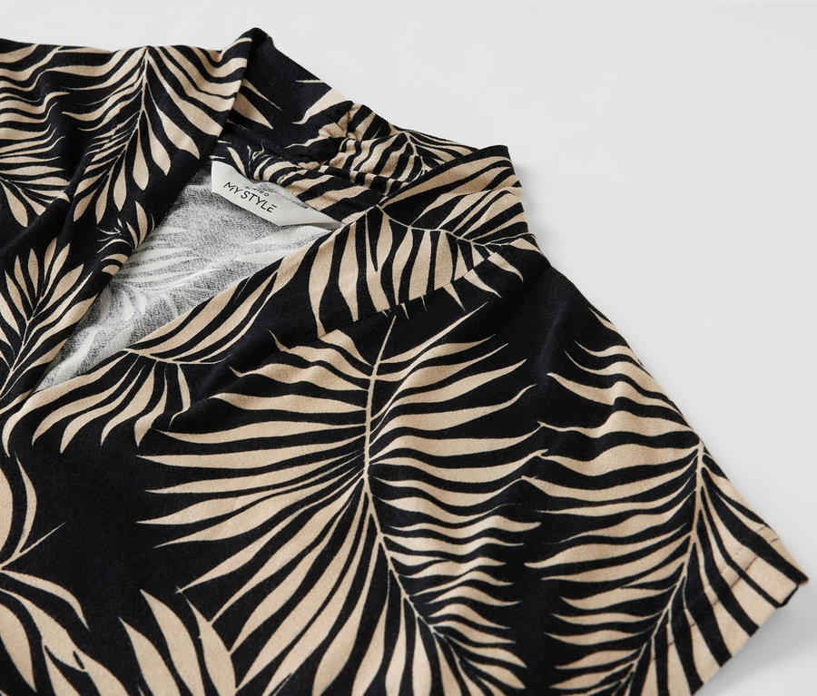 Gros plan sur une blouse imprimée avec encolure en V et motif de feuilles.