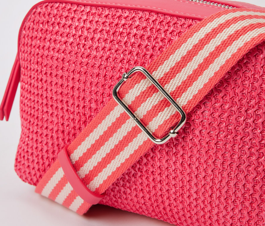 Gros plan d'un sac bandoulière rose avec une sangle rayée.
