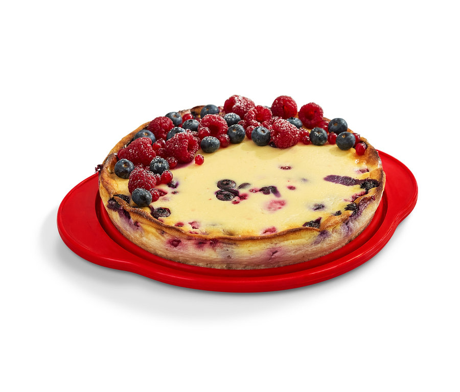 Un gâteau décoré de fruits sur un moule à gâteau pliable rouge.