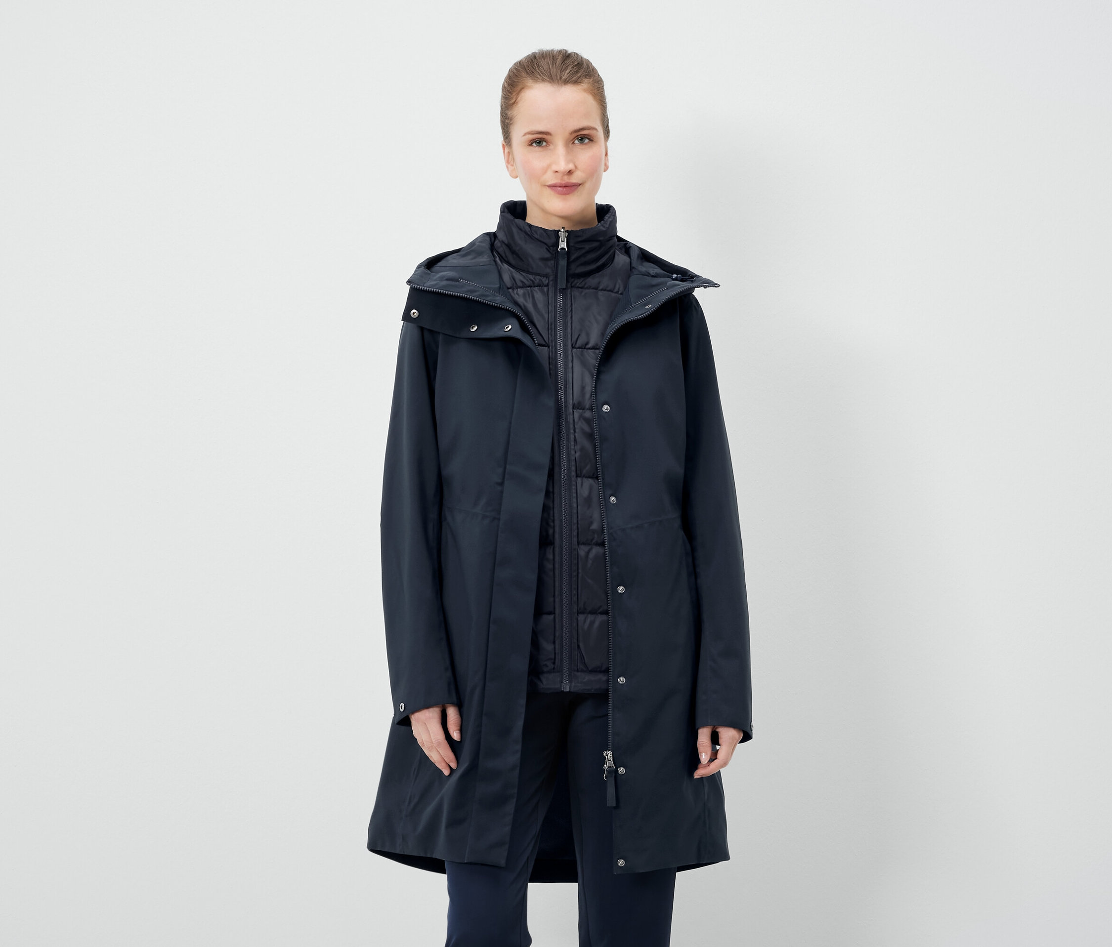 Une femme porte un manteau bleu marine et un gilet.