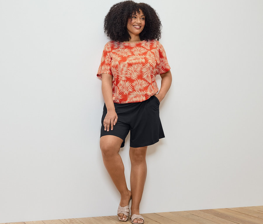 Femme posant en blouse imprimée et short en jersey noir.