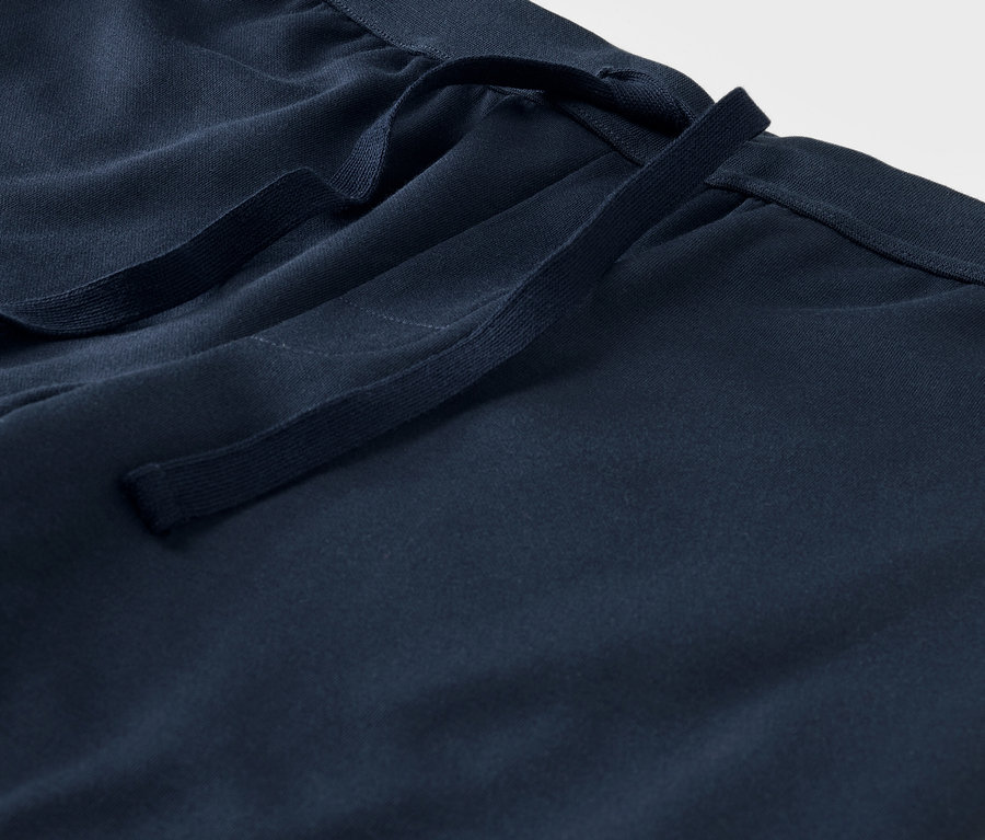 Gros plan sur un pantalon en tissu bleu avec cordon de serrage à la taille.