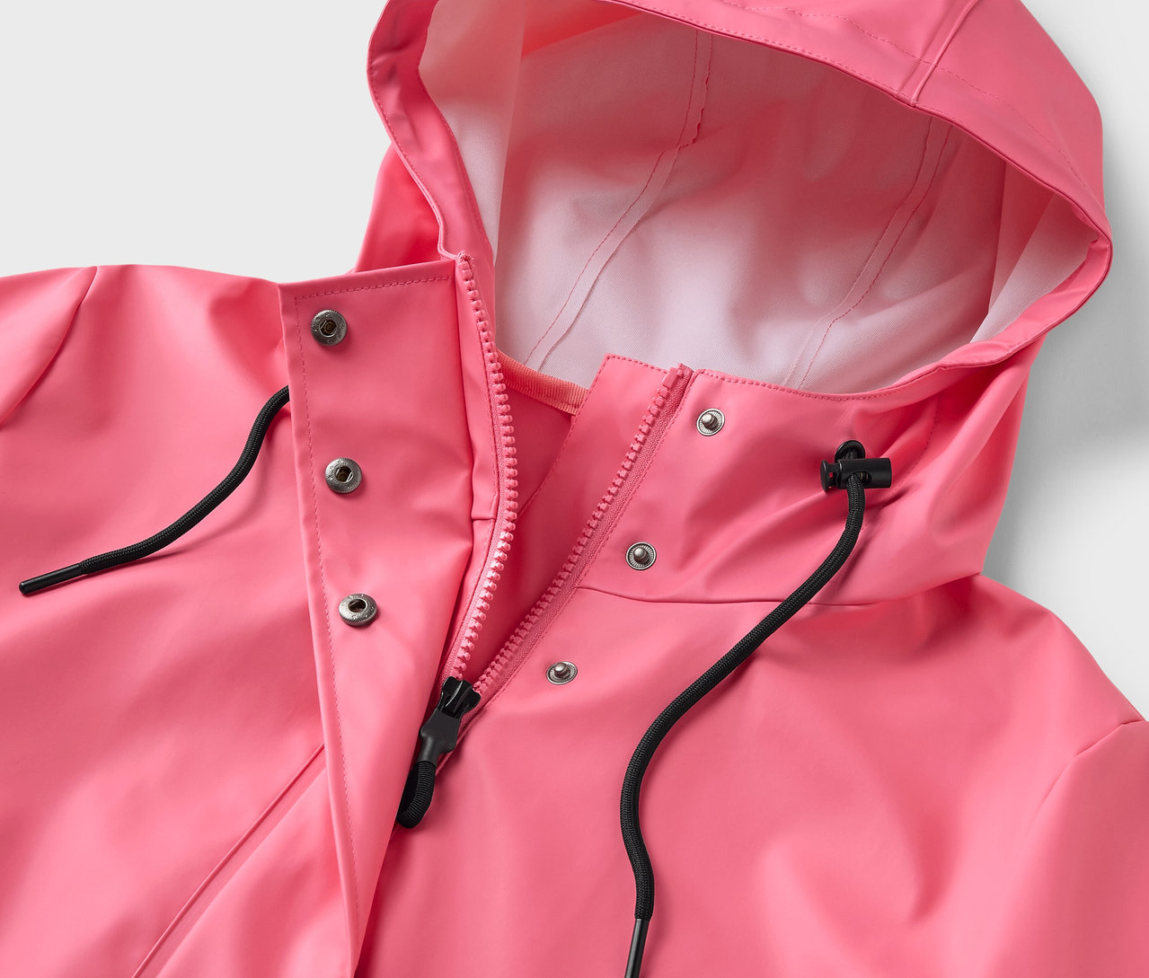 Gros plan sur un manteau de pluie rose avec capuche et fermeture éclair.