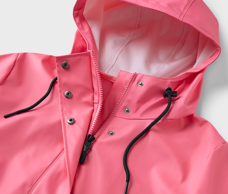 Gros plan sur un manteau de pluie rose avec capuche et fermeture éclair.