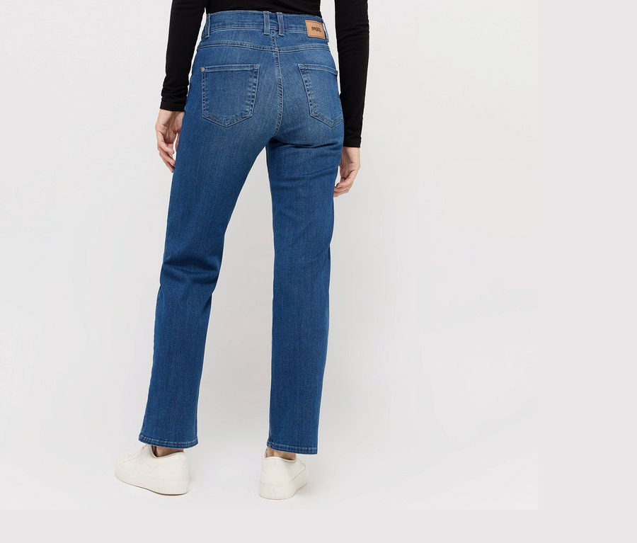 Femme vue de dos portant un jean Angels « Lara » coupe droite, bleu moyen et des baskets blanches.