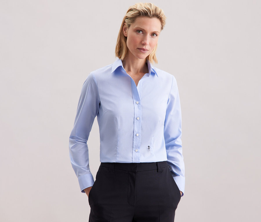 Femme portant un chemisier bleu clair Slim Fit non iron Seidensticker.