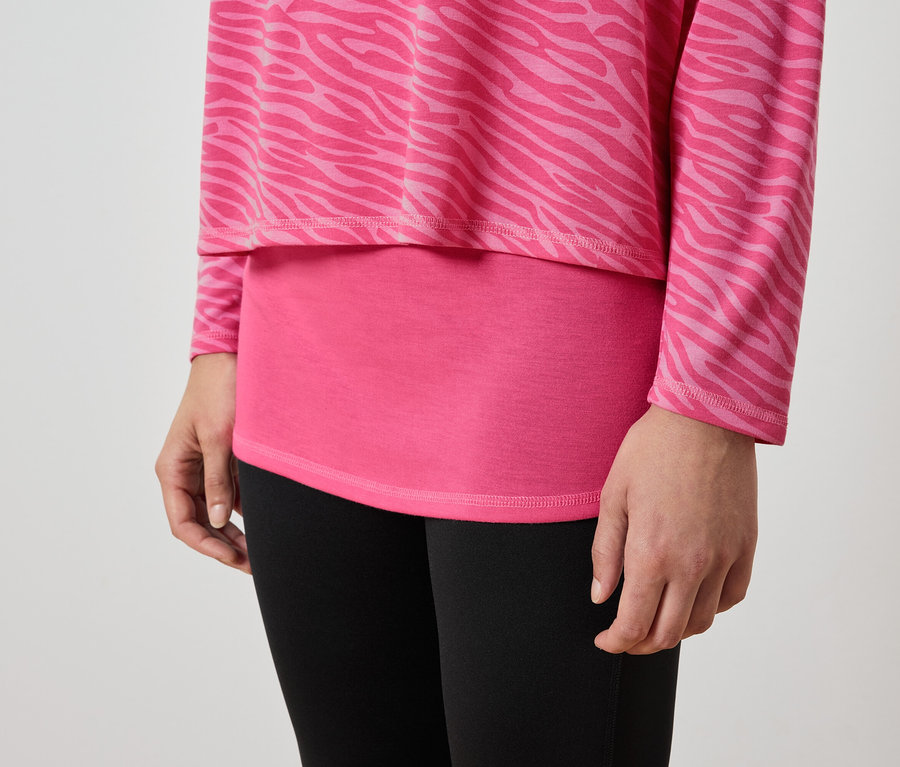 Gros plan d'une femme portant un haut rose à motif animalier et un legging noir.