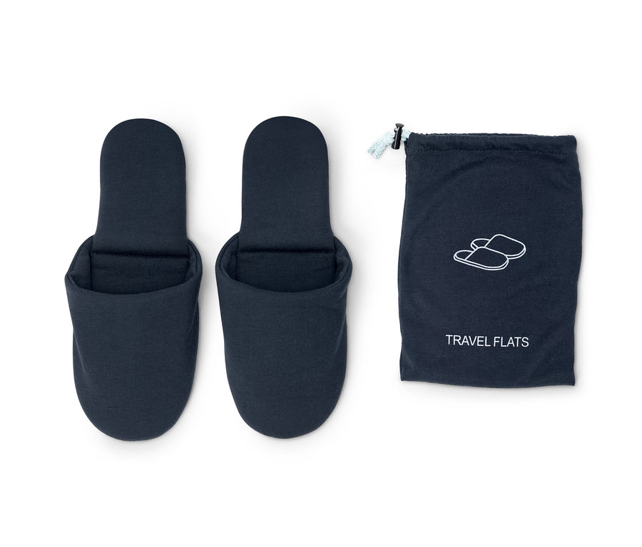 Deux pantoufles de voyage bleues à côté d'un sac bleu.