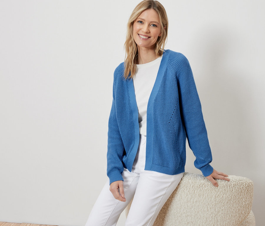 Femme assise portant un cardigan ouvert bleu.