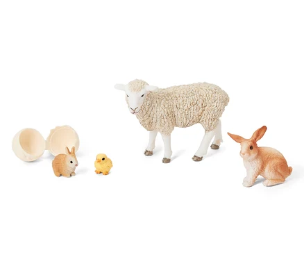 Un œuf ouvert à côté du set Schleich® «Animaux de Pâques» qui comprend un agneau, un lapin et un poussin.