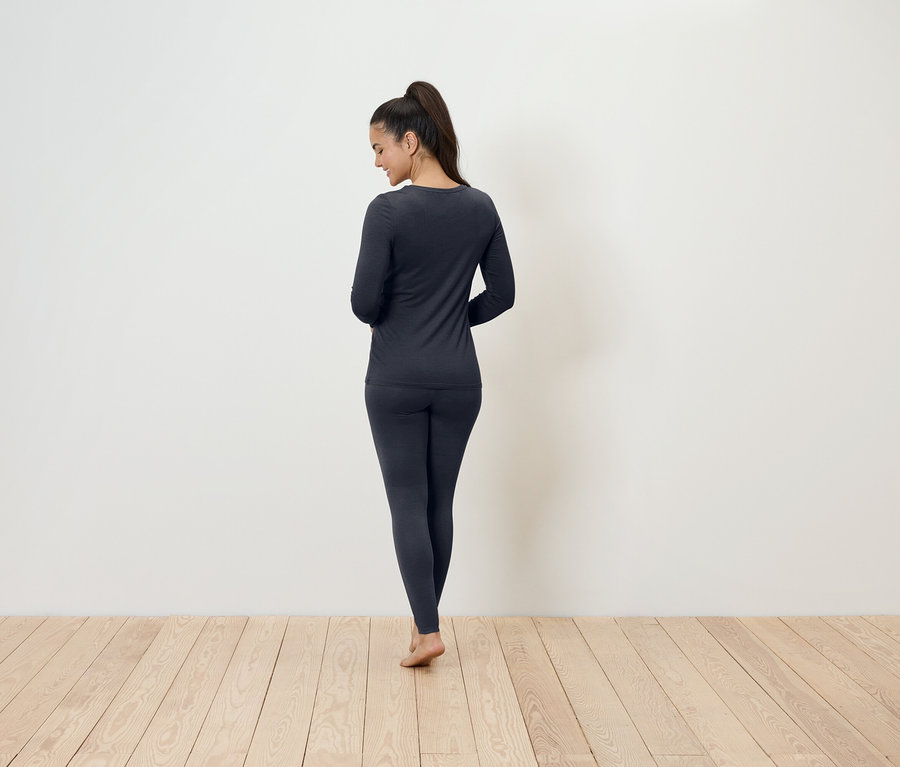Une femme, vue de dos, porte des sous-vêtements thermiques gris foncé.