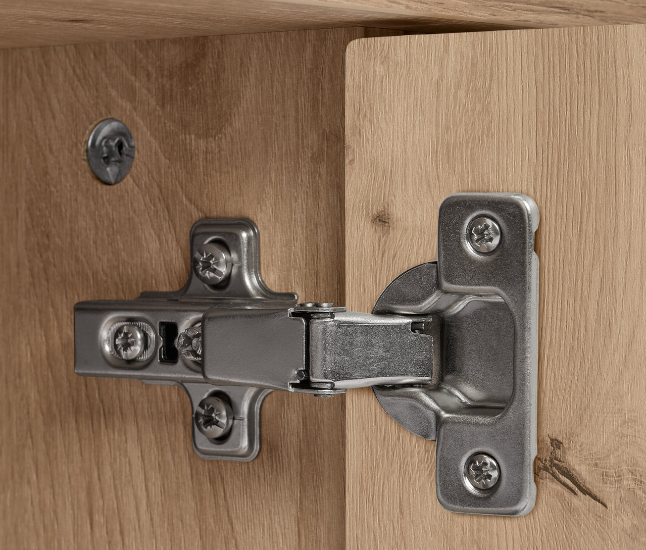 Détail d'une charnière argentée sur un buffet REET en bois.