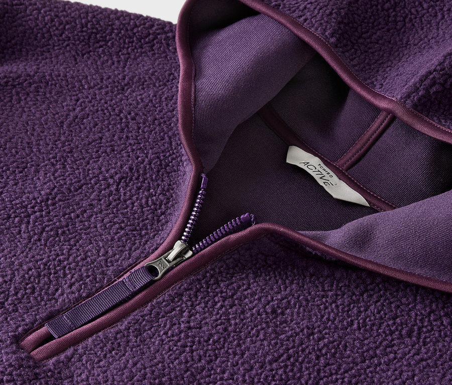 Gros plan sur un pull en polaire violet avec fermeture éclair et étiquette.