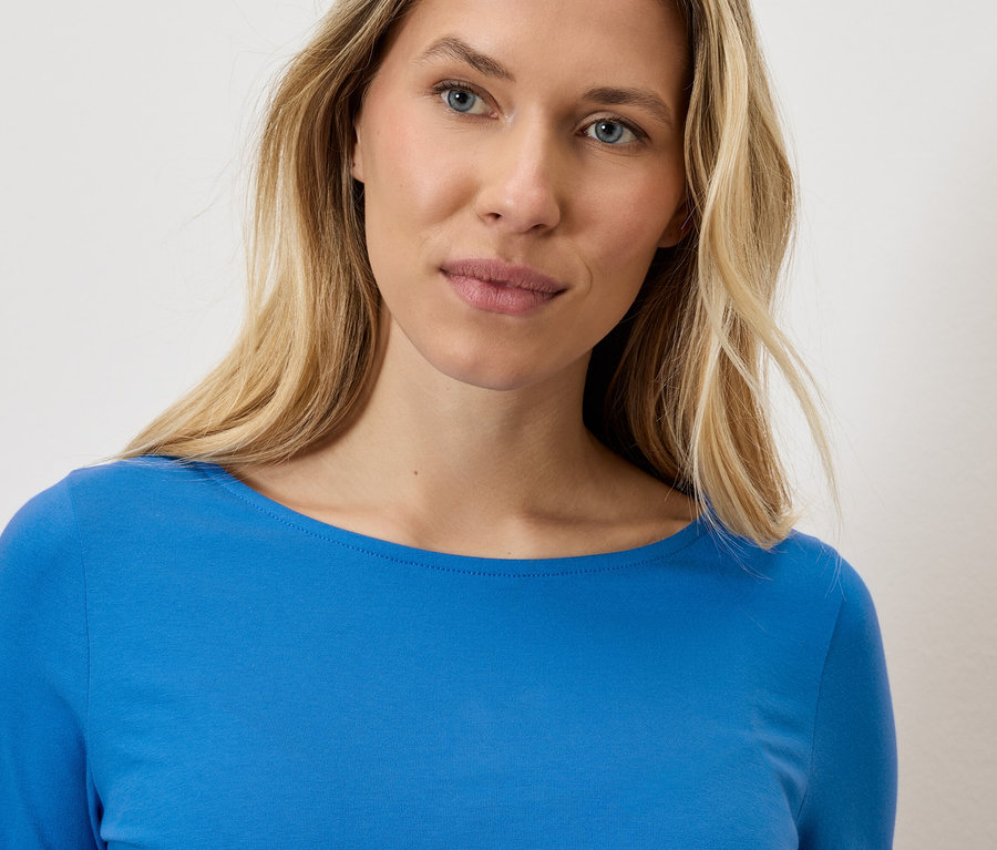 Portrait d'une femme blonde portant un haut bleu à manches longues.