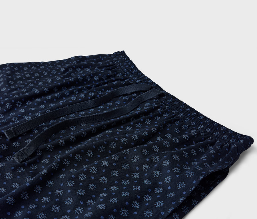 Gros plan d'un pantalon de pyjama bleu marine avec un motif floral bleu et un cordon de serrage.