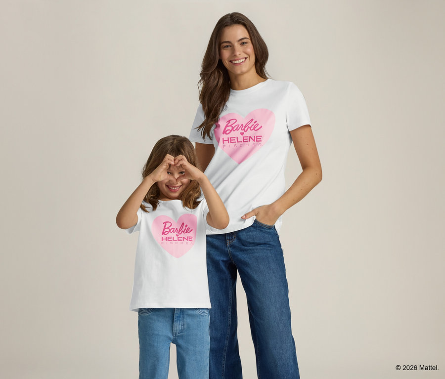 Une femme et une fille souriantes portant des jeans et des t-shirts blancs avec un imprimé cœur rose Barbie posent sur un fond clair.
