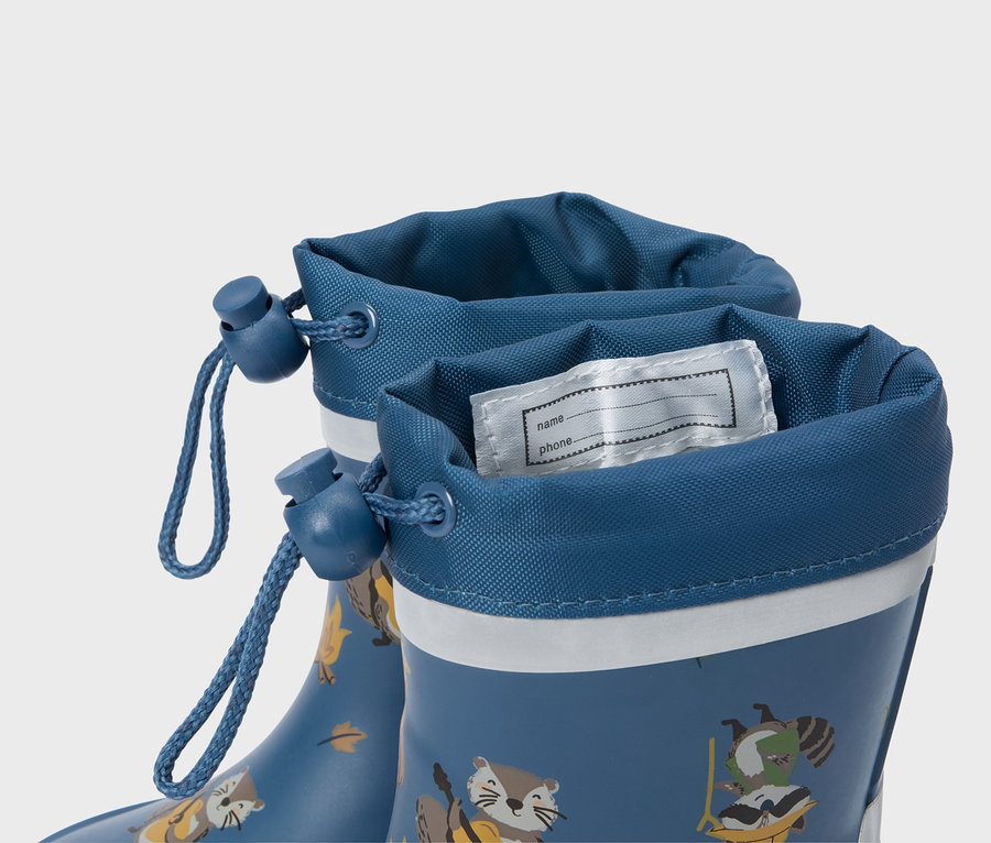 Gros plan sur des bottes en caoutchouc bleues avec des motifs d'animaux et une étiquette de nom à l'intérieur.