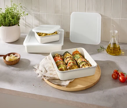 Sur un comptoir de cuisine, plusieurs récipients de stockage rectangulaires remplis avec couvercles, un bol de fromage et une plante.