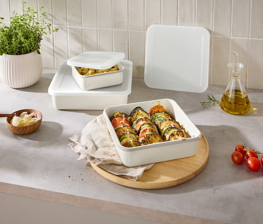 Sur un comptoir de cuisine, plusieurs récipients de stockage rectangulaires remplis avec couvercles, un bol de fromage et une plante.