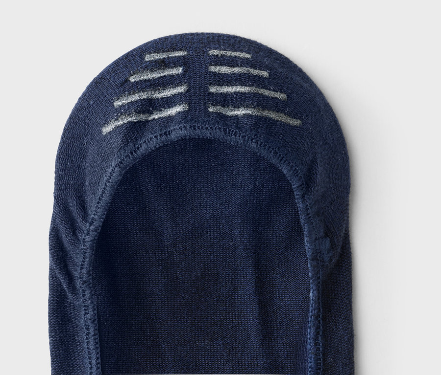 Gros plan d'une socquette bleu marine avec des rayures argentées sur le dessus.