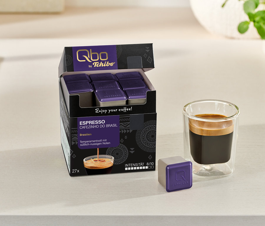 Emballage ouvert de Qbo Espresso CAFEZINHO DO BRASIL avec des capsules et un expresso dans un verre, à côté d'une capsule individuelle.