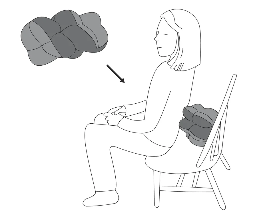 Une femme est assise sur une chaise avec un Coussin de relaxation multifonction dans le dos, un autre coussin flotte au-dessus.
