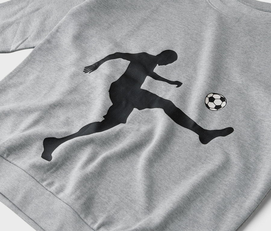 Sur un pull gris, la silhouette d'un joueur de football donnant un coup de pied dans un ballon.