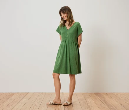Femme portant une robe verte longueur genou et des sandales.