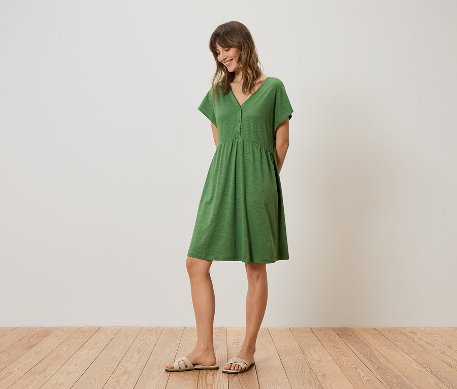 Femme portant une robe verte longueur genou et des sandales.
