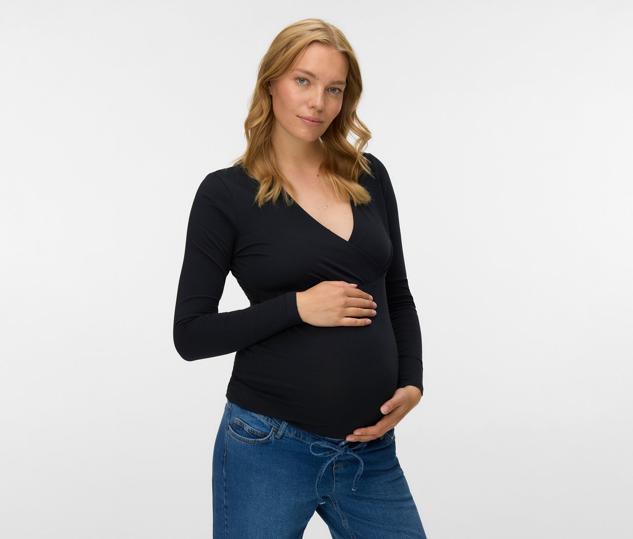 Femme enceinte portant un jean et un haut noir à manches longues MAMALICIOUS «MLKERRIE» (lot de 2) touchant son ventre.