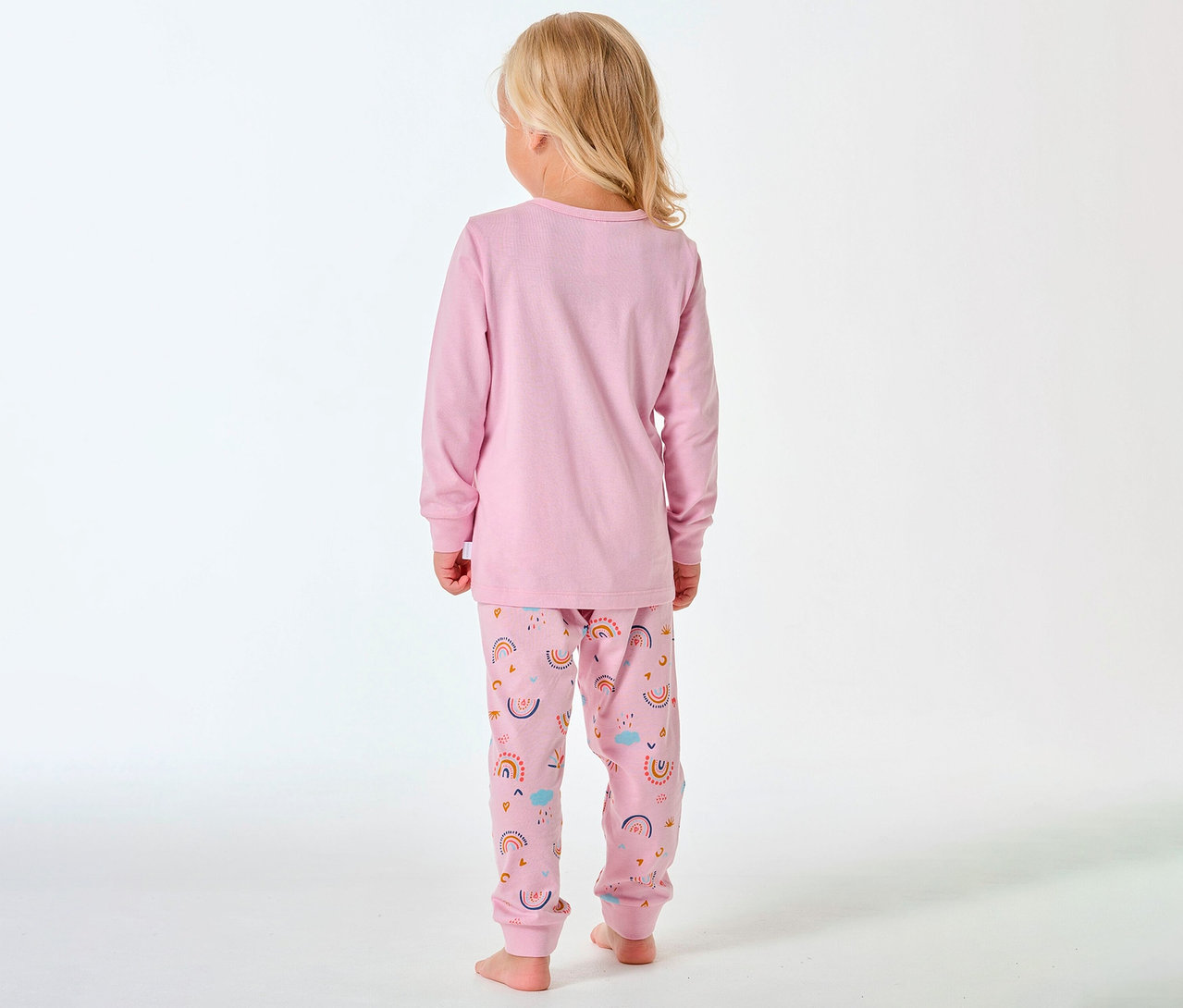 Enfant vue de dos, avec des cheveux blonds, porte un pyjama long pour enfant SCHIESSER à motif arc-en-ciel.