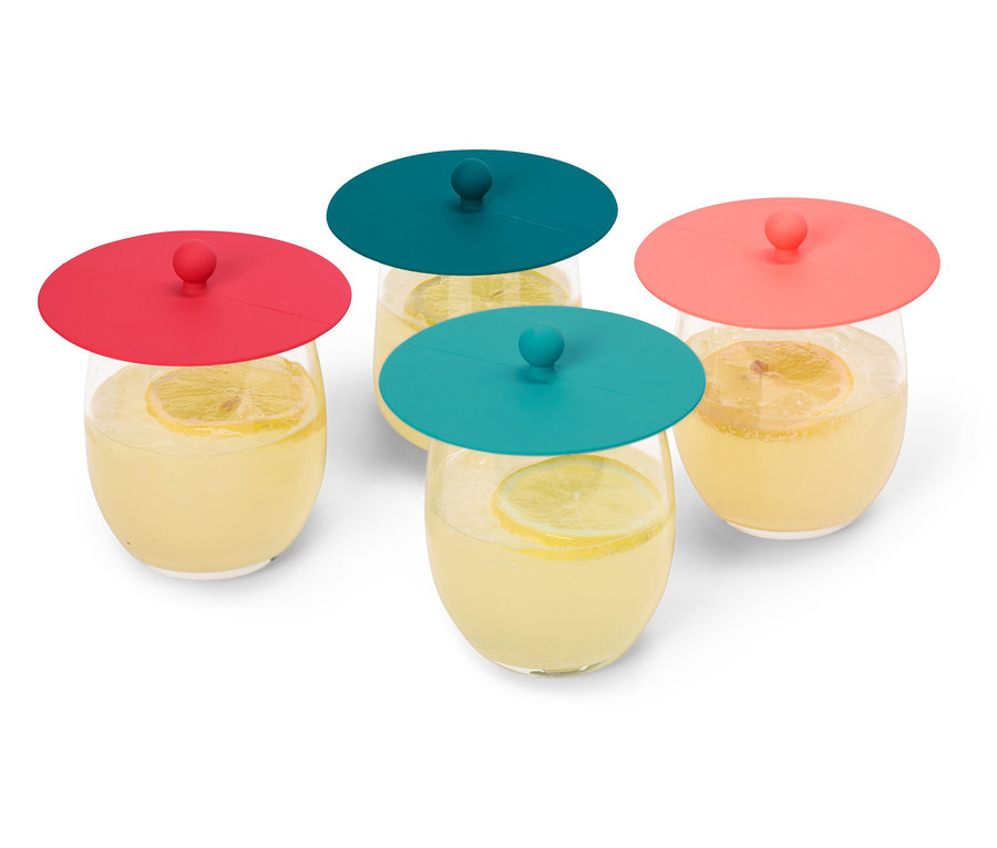 Quatre verres de limonade avec des tranches de citron, recouverts de couvercles en silicone rouges et turquoise, sont posés sur un fond blanc.