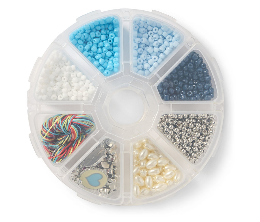 Une boîte ronde transparente avec des compartiments remplis de perles colorées, de breloques et d'une pelote de fil.