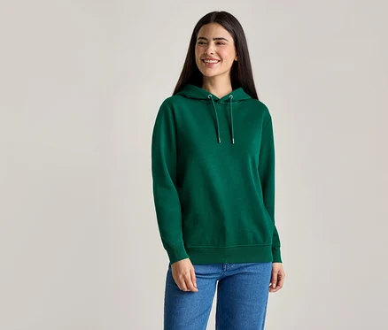 Une femme aux longs cheveux foncés porte un sweat à capuche vert et un jean bleu.