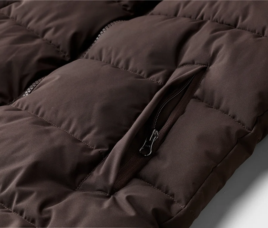 Gros plan sur un gilet matelassé marron avec une fermeture éclair sur la poche.