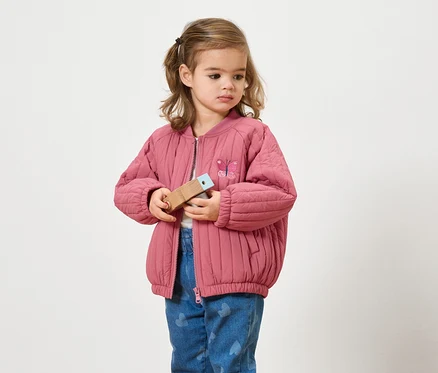 Fille avec une veste rose tenant un jouet en bois.