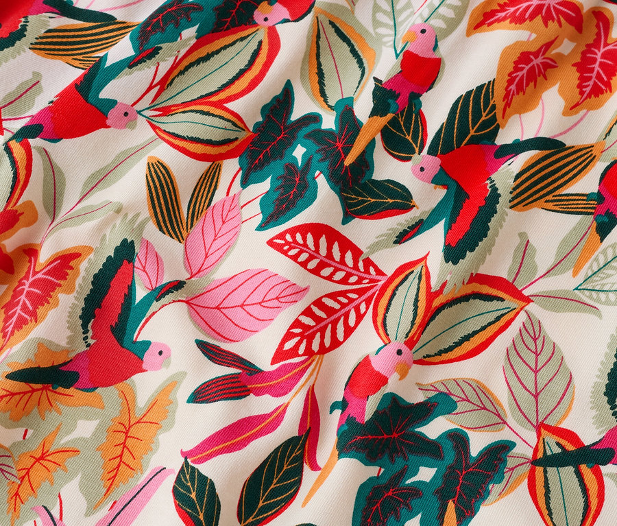 Gros plan d'un tissu avec un motif de feuilles colorées et de perroquets.