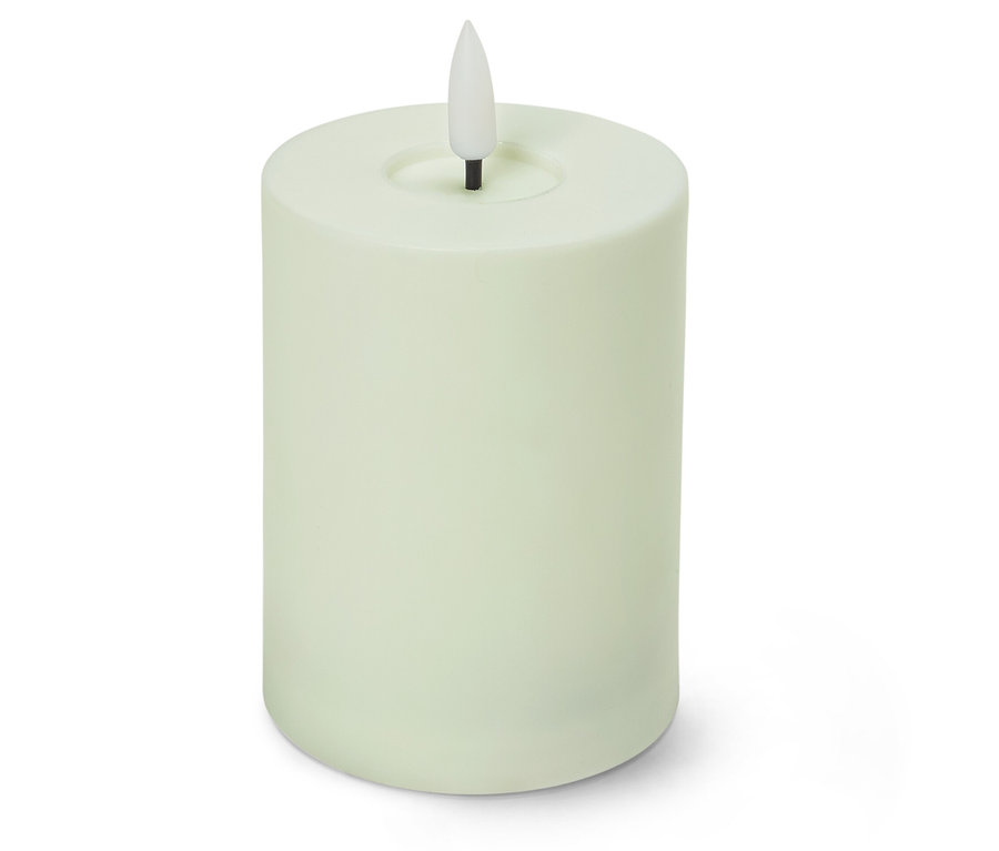 Une bougie pilier vert clair avec une flamme LED blanche en forme de goutte est posée devant un fond blanc.