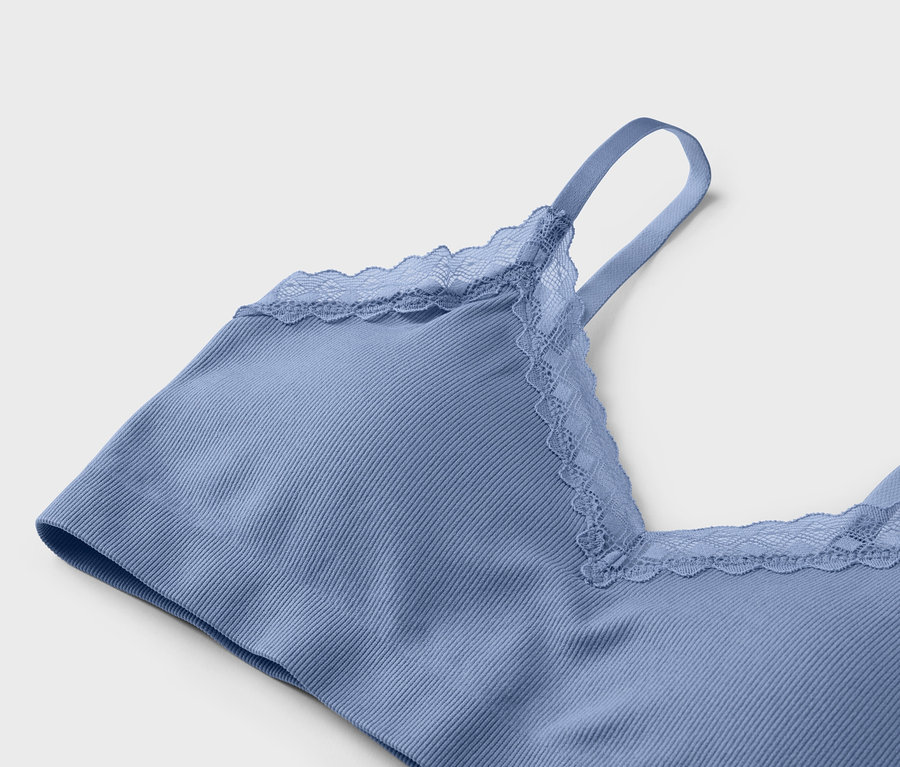 Gros plan d'un soutien-gorge bleu clair côtelé avec de la dentelle à l'encolure et aux bretelles sur un fond gris clair.