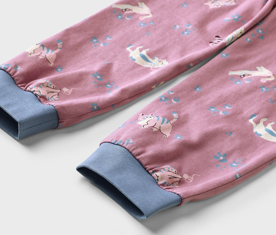 Deux manches de vêtement roses avec des poignets côtelés bleus, ornées d'un motif de chats blancs et bleus et de petites fleurs bleues.