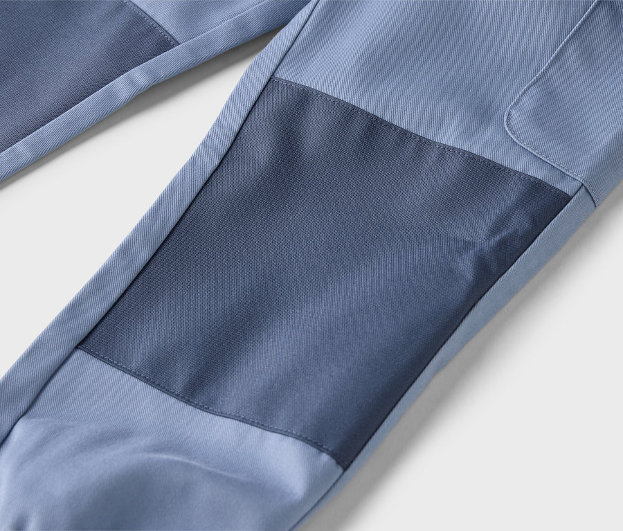 Gros plan d'un pantalon bleu avec des pièces rapportées bleues plus foncées.
