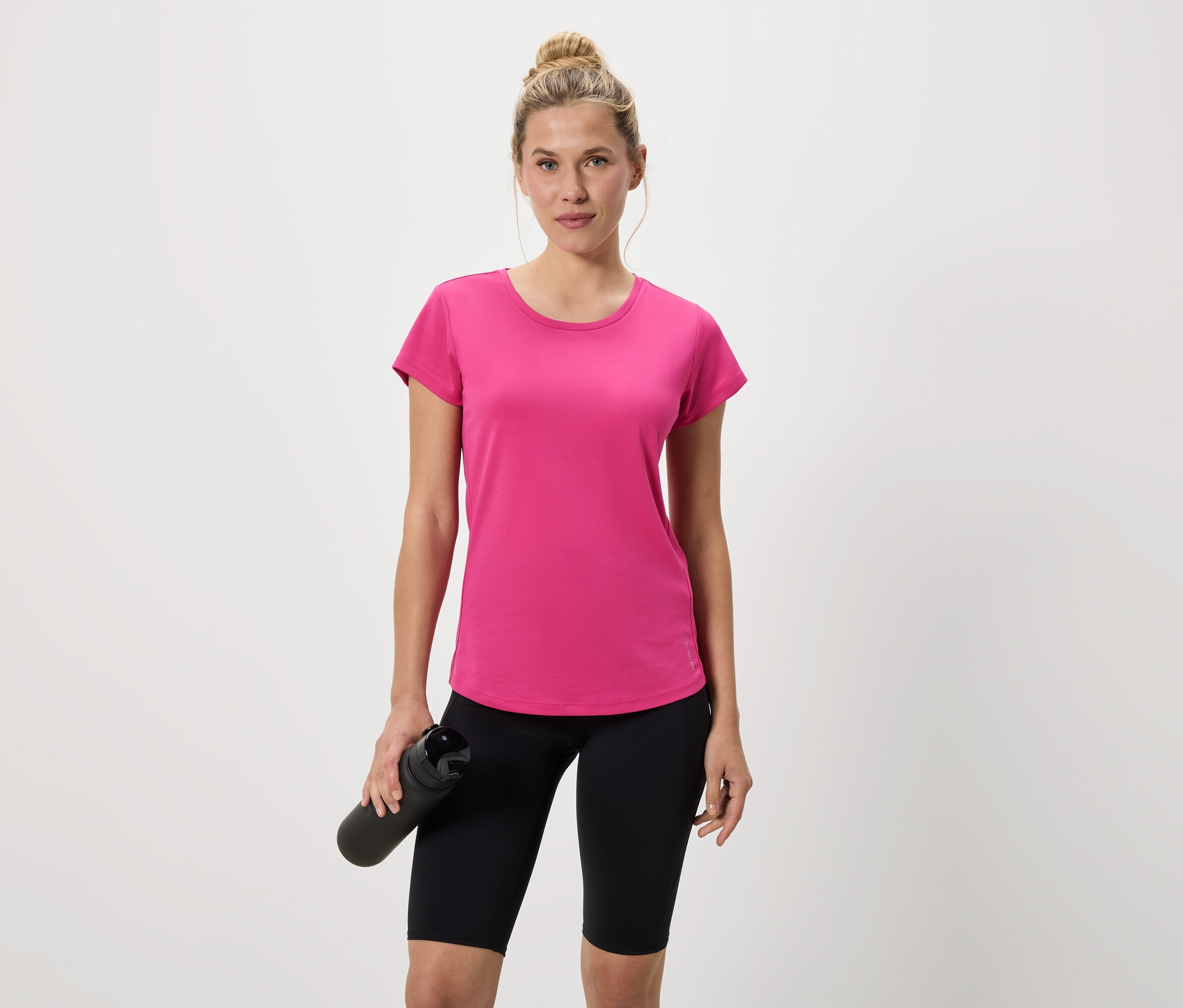 Femme en t-shirt rose et cycliste noir tenant une bouteille d'eau noire.